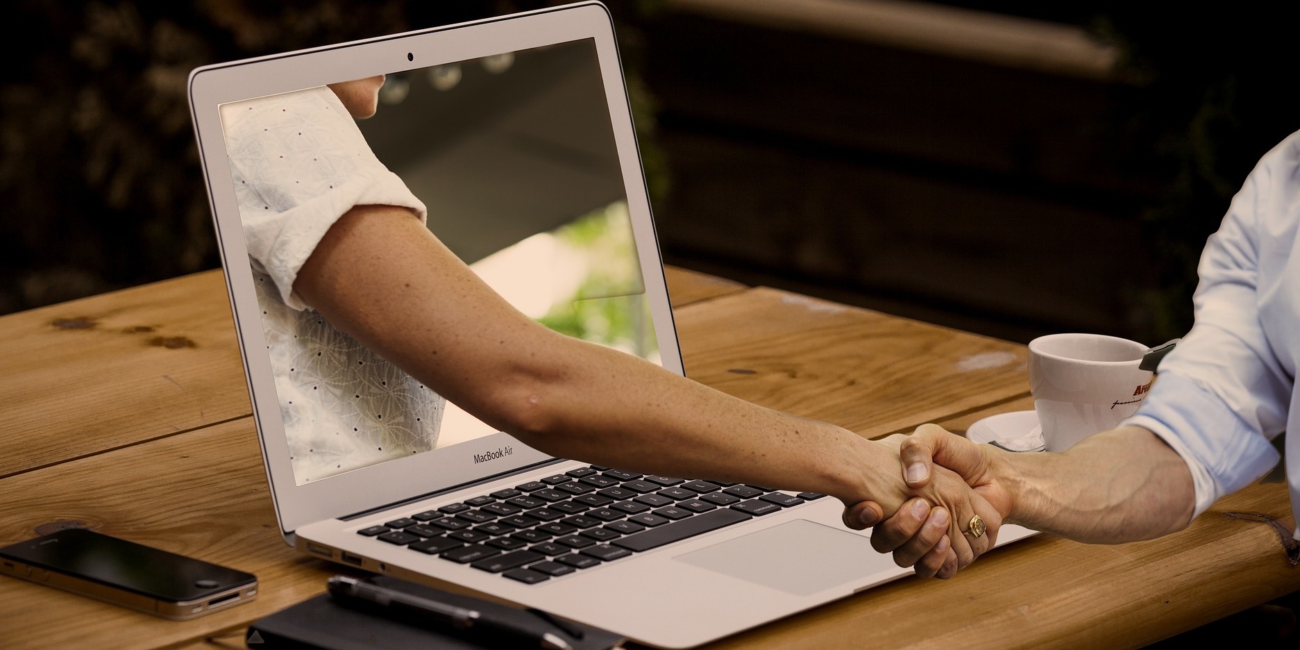 someone shakes a hand coming out of their computer