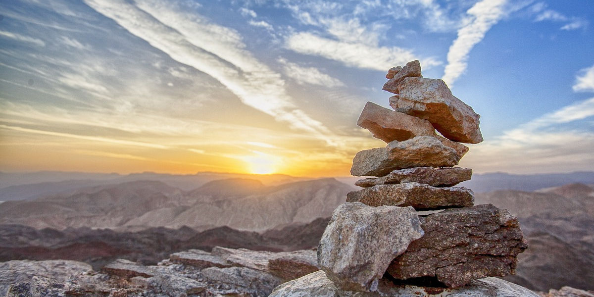 A set of stones balanced on top of each other in front of a distant sunset.